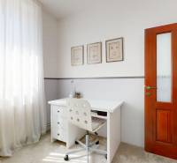 Arbeitsbereich in einem Einfamilienhaus mit Schreibtisch, gepolstertem Stuhl und Holztüren.