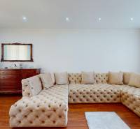 Wohnzimmer in einem Einfamilienhaus mit heller Couchgarnitur und Holzanrichte.