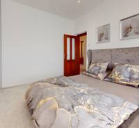 Schlafzimmer im Einfamilienhaus mit Bett und Lampe, Schrank gegenüber dem Kopfende des Bettes.