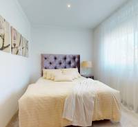 Schlafzimmer im Einfamilienhaus mit hellem Bett, Dekorationen und großem Fenster.