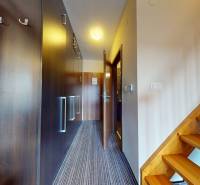 Flur einer 2-Zimmer-Wohnung mit Einbauschränken und Holztreppe.