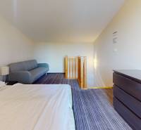 Schlafzimmer in einer Zweizimmerwohnung mit Bett, Sofa und Kommode.