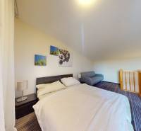 Schlafzimmer in einer 2-Zimmer-Wohnung mit einem bequemen Bett und einem Geländer an der Treppe.