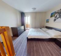 Schlafzimmer in einer Zweizimmerwohnung mit Treppe, großem Bett und Fotos an der Wand.