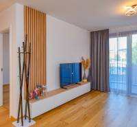 Wohnzimmer in einer 3-Zimmer-Wohnung mit TV, verglastem Balkon und Holzboden.