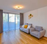 Wohnzimmer mit Holzboden, grauen Möbeln und großem Fenster in einer 3-Zimmer-Wohnung.