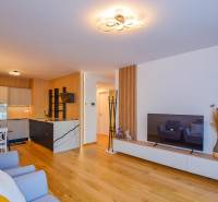 Wohnzimmer mit offener Küche; Holzboden, Esstisch, Fernseher, 3-Zimmer-Wohnung.