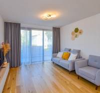 Wohnzimmer mit bequemer Couch, Holzboden und Fernseher in einer 3-Zimmer-Wohnung.