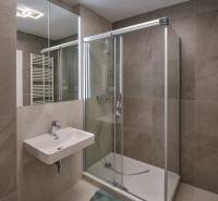 Badezimmer in einer 3-Zimmer-Wohnung mit Waschbecken, Duschkabine und Spiegel mit Fliesen.
