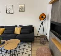 Wohnzimmer in einer 3-Zimmer-Wohnung mit schwarzem Sofa und dekorativer Beleuchtung.