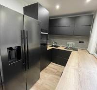 Küche in einer 3-Zimmer-Wohnung mit schwarzen Geräten und Holzboden.