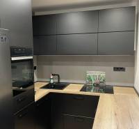 Küche in einer 3-Zimmer-Wohnung mit schwarzen Schränken und einer Holzarbeitsplatte.