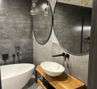 Badezimmer in einer 3-Zimmer-Wohnung mit stilvollen Spiegeln, Badewanne und Waschtisch aus Holz.