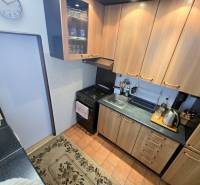 Küchenzeile in einer 3-Zimmer-Wohnung mit Holzschränken und schwarzen Arbeitsplatten.