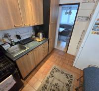 Küche in einer 3-Zimmer-Wohnung mit Holzschränken und Geräten, Raum verbunden mit dem Wohnzimmer.