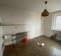 Eine leere Küche mit einfacher Ausstattung in einer 3-Zimmer-Wohnung, weiße Wände, Heizkörper.