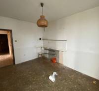 Eine leere Küche in einer 3-Zimmer-Wohnung mit einem ungewöhnlichen Kronleuchter und einem unfertigen Boden.