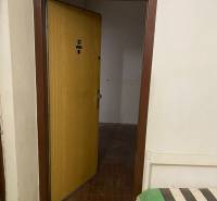 Offene Tür in einer 3-Zimmer-Wohnung mit Fliesenboden und einer Bank mit buntem Überwurf.