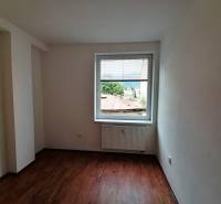 Ein leerer Raum mit Holzboden und einem Fenster in einer Zweizimmerwohnung.