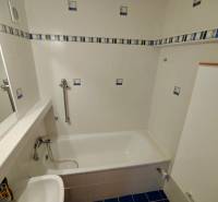 Ein Badezimmer mit hellen Fliesen, einer Badewanne und einem Waschbecken in einer 3-Zimmer-Wohnung.