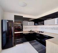 Küche in einer 3-Zimmer-Wohnung mit schwarzen glänzenden Schränken und einem Eckherd.
