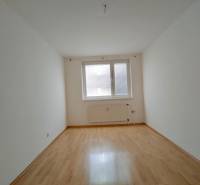Ein Zimmer in einer 3-Zimmer-Wohnung mit einem Boden in Holzoptik und weißen Wänden.