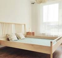 Schlafzimmer mit hellen Holzmöbeln und großem Fenster in einer Zweizimmerwohnung.