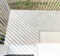 Ein Balkon mit Betonboden und Metallgeländer, der zum Garten ausgerichtet ist.
