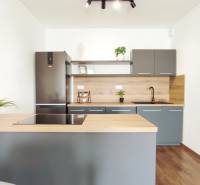Küche in einer 2-Zimmer-Wohnung mit dunkelgrauer und hölzerner Küchenzeile.