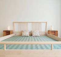 Helles Schlafzimmer mit Holzbett und Kissen in einer Zweizimmerwohnung.
