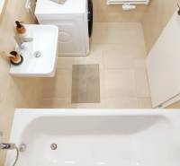 Badezimmer mit Badewanne, Waschbecken, Waschmaschine und Handtuchheizkörper in einer 2-Zimmer-Wohnung.