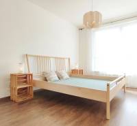Helles Schlafzimmer mit Holzbett und Nachttischen in einer Zweizimmerwohnung.