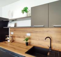 Küche in einer 2-Zimmer-Wohnung mit grauen Schränken und einer Holzarbeitsplatte.