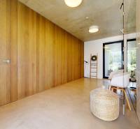 Minimalistischer Flur in einem Einfamilienhaus mit Holzwand, Korbgeflecht und modernen Stühlen.