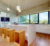Eine Küche in einem Einfamilienhaus mit großen Fenstern, Holzboden und weißen Schränken.