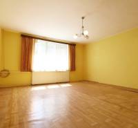 Ein Zimmer in einem Einfamilienhaus mit gelben Wänden, Holzboden und einem zentralen Kronleuchter.