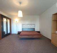 Stilvolles Interieur einer Einzimmerwohnung mit Bett, Einbauschrank und Regalen.