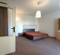 Helles Schlafzimmer in einer Einzimmerwohnung mit Bett, Lampe und Möbeln.