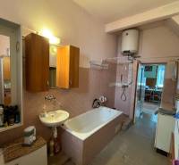 Ein Badezimmer in einem Einfamilienhaus mit Dusche, Badewanne und Holzschränken.