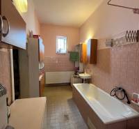 Ein Badezimmer in einem Einfamilienhaus mit Badewanne, Waschbecken und Schränken, gemütliche Einrichtung.