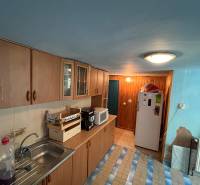 Eine Küche in einem Einfamilienhaus mit Holzschränken, einer Mikrowelle und einem Kühlschrank.