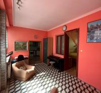 Wohnzimmer in einem Einfamilienhaus mit orangefarbenen Wänden, einem Sessel und kariertem Boden.