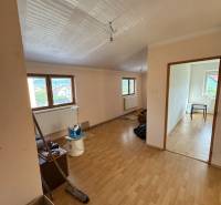 Ein Zimmer mit Holzboden und Fenstern in einem Einfamilienhaus, bereit für die Renovierung.