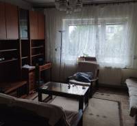 Wohnzimmer in einem Einfamilienhaus mit Holzmöbeln, Couchtisch und Vorhängen.