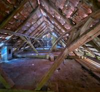 Das Dachgeschoss eines Einfamilienhauses mit Holzbalken und einem erhaltenen Ziegeldachsystem.