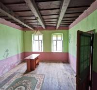 Ein Zimmer in einem Einfamilienhaus mit einer Holzdecke, einem alten Tisch und einem Teppich.
