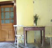 Gelbe Wände in einem Einfamilienhaus mit einem Holztisch, Stühlen und einer kleinen Vase mit Blumen.