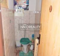 Badezimmer in einem Einfamilienhaus mit Toilette und grünem Sitz.