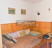 Innenraum eines Einfamilienhauses mit Sofa, Bildern an der Wand und Holzverkleidung.