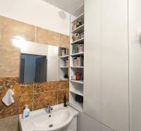 Badezimmer in einer 3-Zimmer-Wohnung mit weißem Waschbecken, Spiegel und Aufbewahrungsschränken.